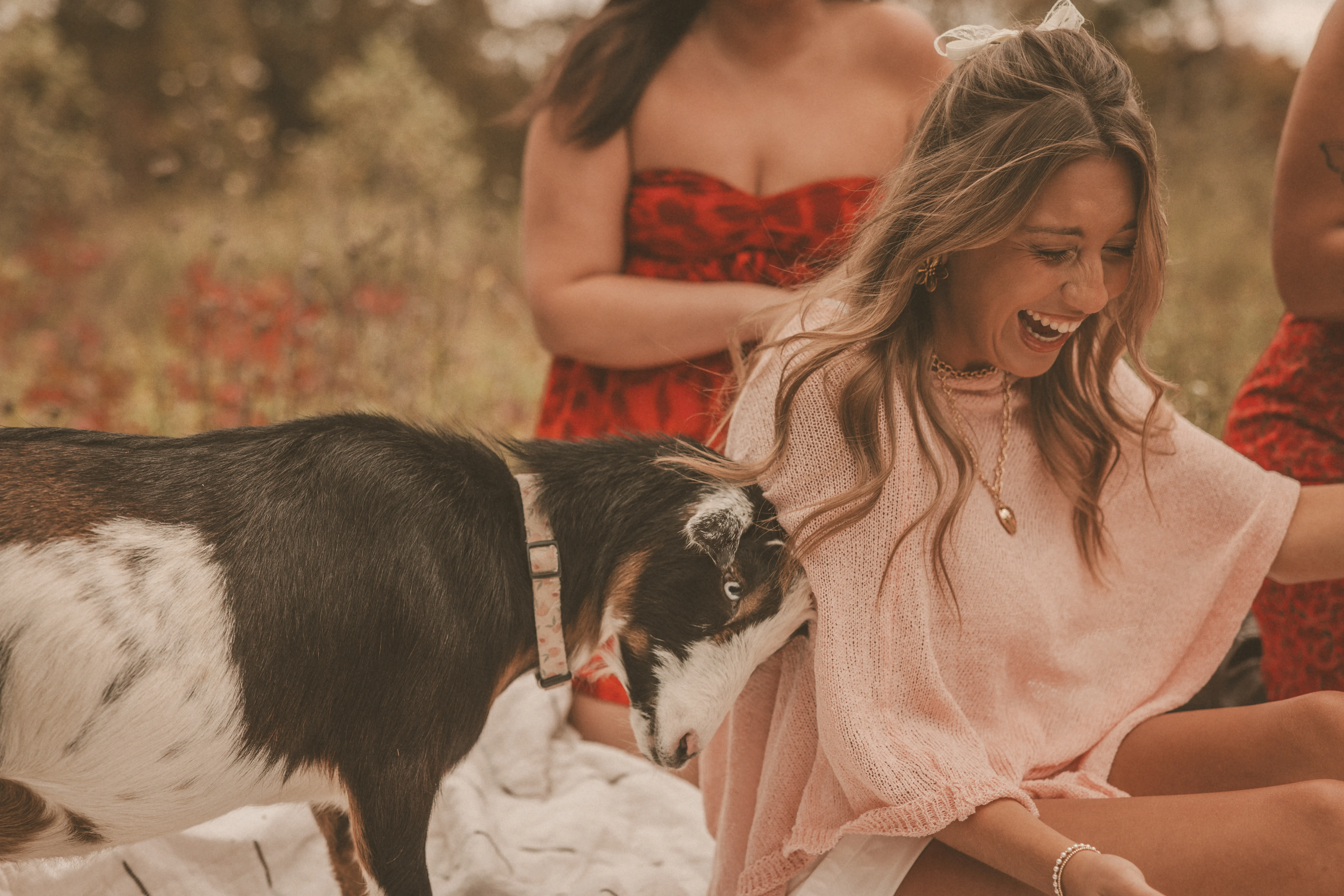 Two women in red dresses taking photos in front of an ornate floor mirror propped in a field at Magnolia Hill
