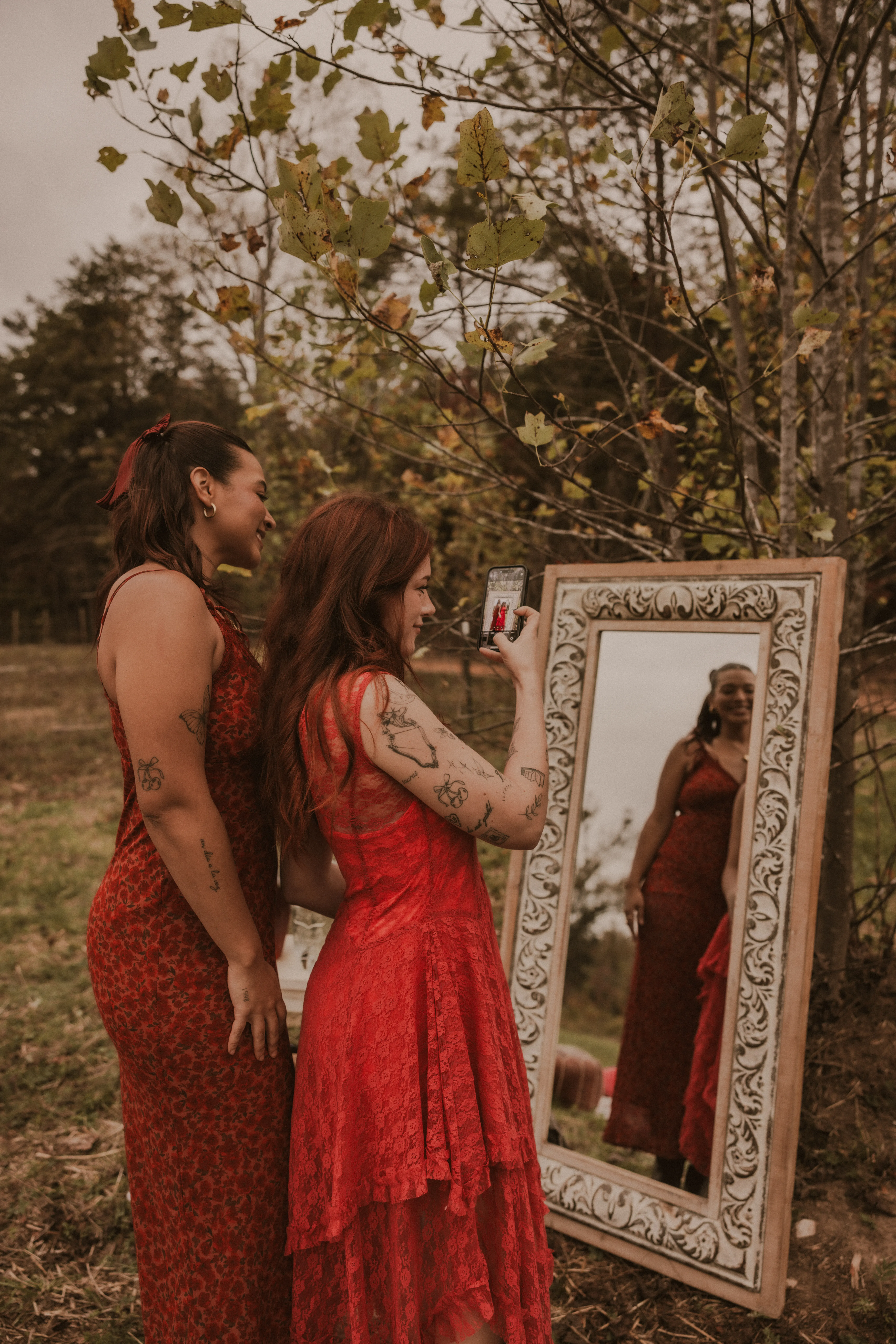 Women in colorful dresses raising glasses in a toast around a farm table on a blanket at Magnolia Hill